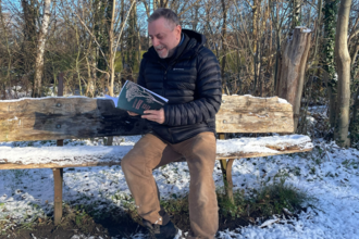 Image of NWT CEO, Mike Pratt, sitting on a bench on a snow-covered St Nicholas Park nature reserve.