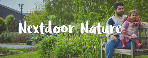 A smiling man and a girl in colourful clothing sit on a wooden bench in a vibrant green garden, with greenery and flowers around them, with text reading “Nextdoor Nature”.