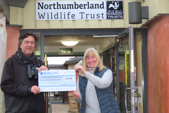 Mike Fielding from Birdersmarket handing over a cheque for £450 to Carolyn McMahon, Hauxley Wildlife Discovery Centre Reception and Information Assistant, image Sheila Luck.
