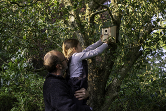 Man and child putting up a bird box. 