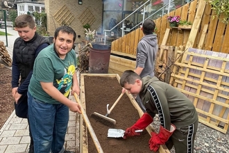 Image of young people working around a large wooden plant bed.