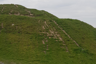 Image of Northumberlandia with grass worn away where people have been walking over it.
