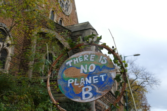 Circular protest sign at a climate march. The sign is painted to look like the earth, and reads "There is no planet B."