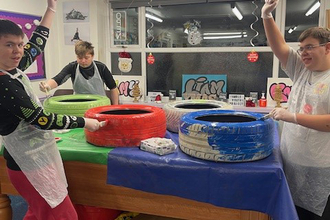 Members of the Amble Youth Project painting car tyres for the garden. Image by: Demmi Robinson.