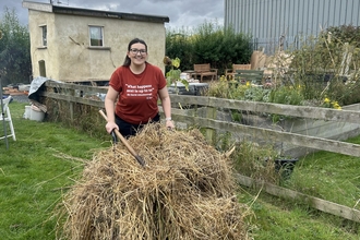 Woman in red t-shirt with a wheelbarrow full of hay