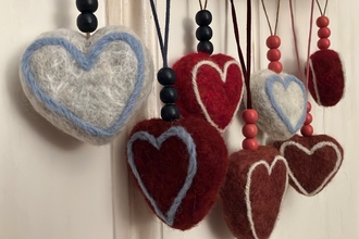 Seven needle-felted heart decorations.