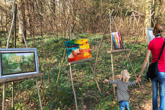 Mother and child looking at a outdoor art gallery in a woodland setting.
