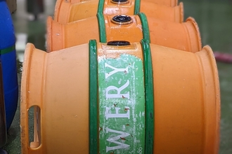 Orange beer barrels on the floor in a row. Image by Allendale Brewery.