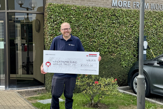 Graham Holyoak (NWT) standing in front of Egger UK building with a large cheque. Image by Egger Hexham.