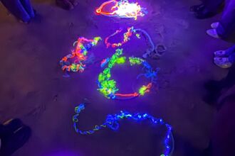 Young people standing around illuminated marine plastic. Image by Rhiannon Studholme.