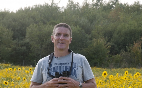 Iolo stands in a field of sunflowers