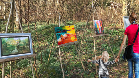 Mother and child looking at a outdoor art gallery in a woodland setting.