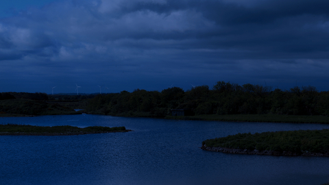 A night time image of a nature reserve with a lake and trees.