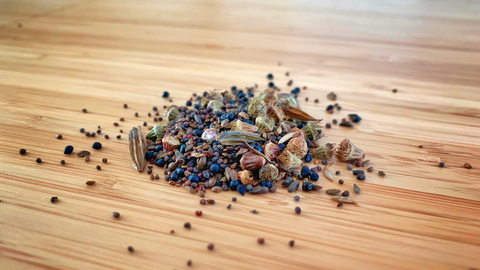 A pile of wildflower seeds on a wooden surface.