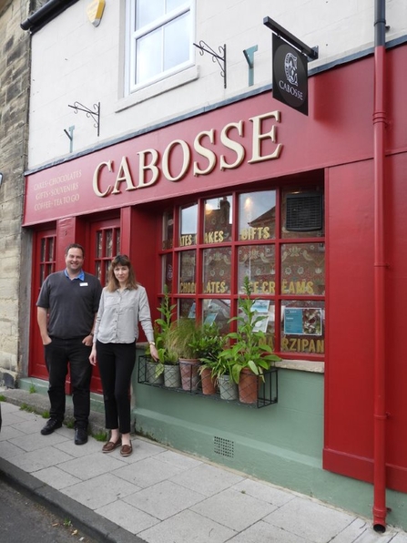 Alex Lister, Northumberland Wildlife Trust’s Wilder Druridge Manager with Louise Keeble, Cabosse owner and chocolate creator, standing outside of the Cabosse storefront.