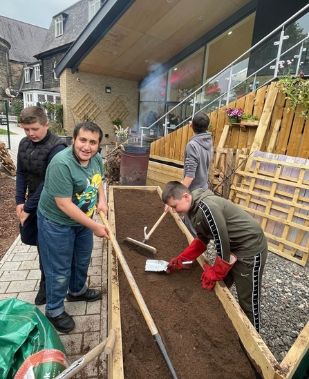 Image of young people working around a large wooden plant bed.