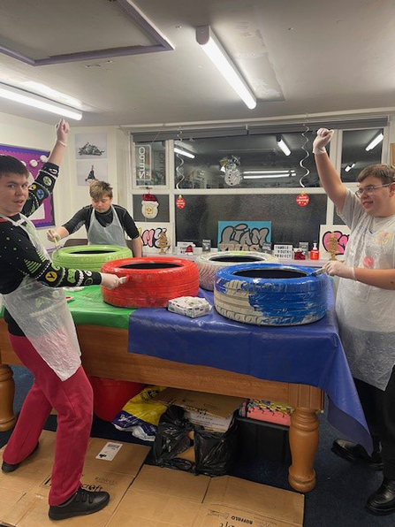 Members of the Amble Youth Project painting car tyres for the garden. Image by: Demmi Robinson.