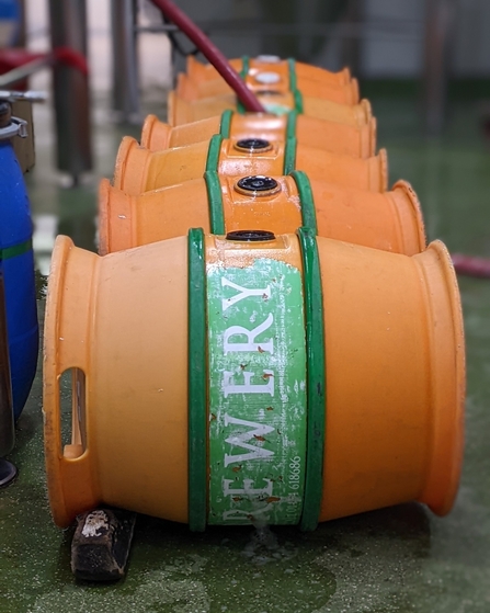 Orange beer barrels on the floor in a row. Image by Allendale Brewery.