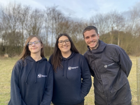 Three people in NWT branded clothes posing for a picture outside.