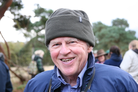 Dr Angus Lunn MBE smiling for the camera in front of a group of people. Image by Duncan Hutt.