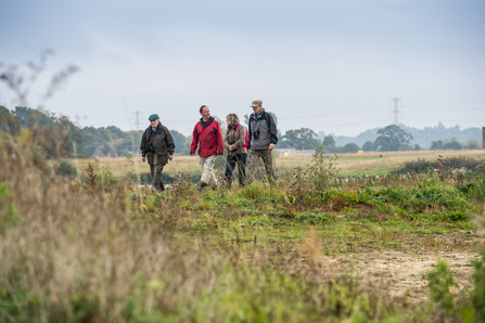 Four people in outdoor ware walking in a field.