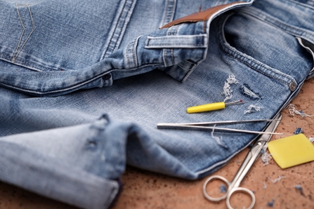 Pair of jeans with scissors in the foreground.