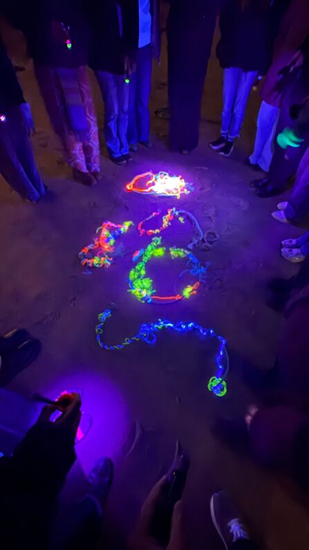 Young people standing around illuminated marine plastic. Image by Rhiannon Studholme.
