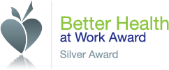 Logo for the Better Health at Work Award showing a stylised grey heart with a leaf shape, alongside green and blue text reading “Better Health at Work Award” and “Silver Award.”