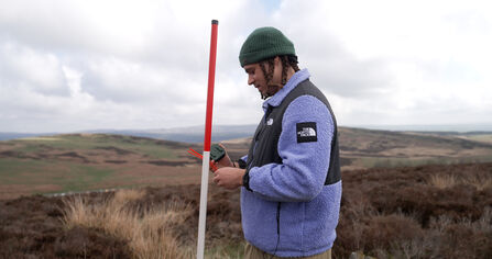 A side view of The Wildlife Trusts' ambassador Louis VI installing an acoustic monitor. 