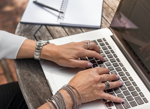 Hands typing on a silver laptop